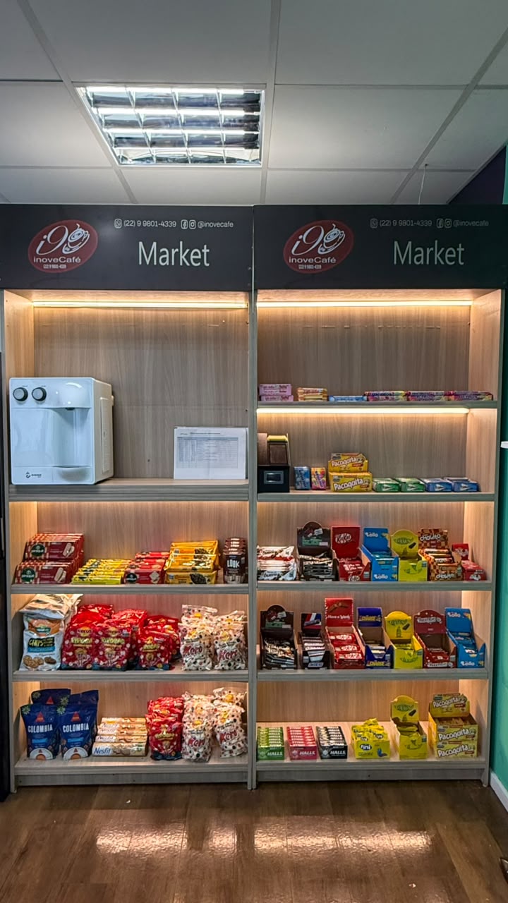Dois módulos de prateleiras iluminadas com snacks, bebedouro e ponto de pagamento.